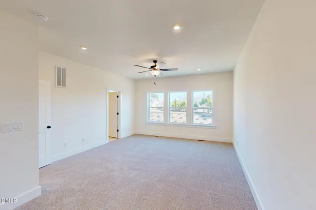 an empty room with ceiling fan and window