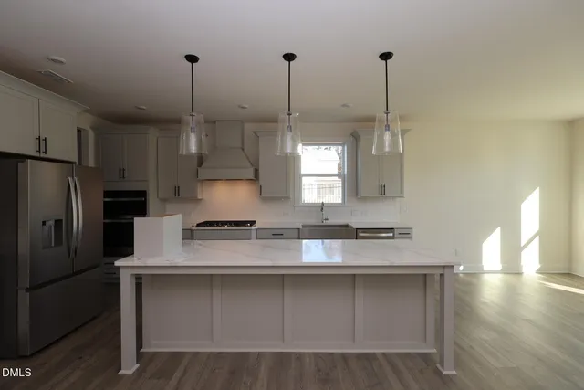 a large kitchen with stainless steel appliances kitchen island a large counter top and a wooden floors