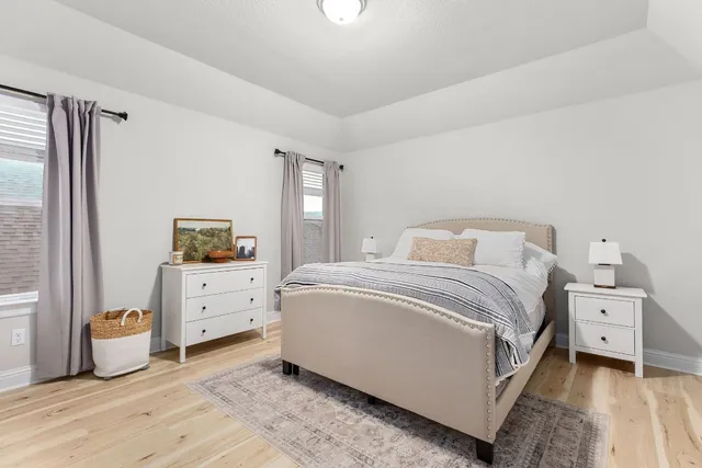 a spacious bedroom with a bed and a flat tv screen on dresser
