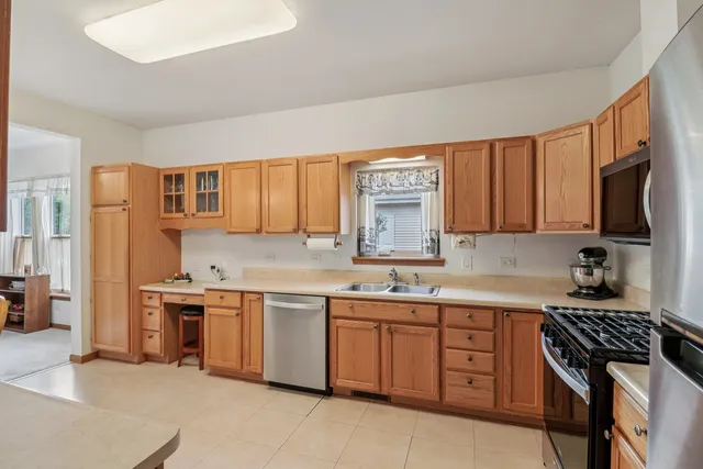 a kitchen with a sink a counter top space stainless steel appliances cabinets and a window