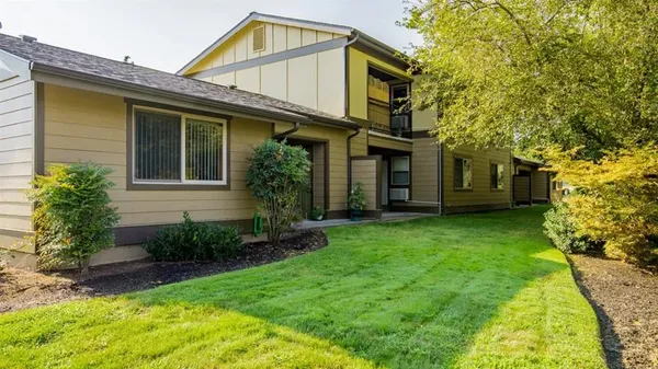 a view of a house with brick walls and a yard with plants