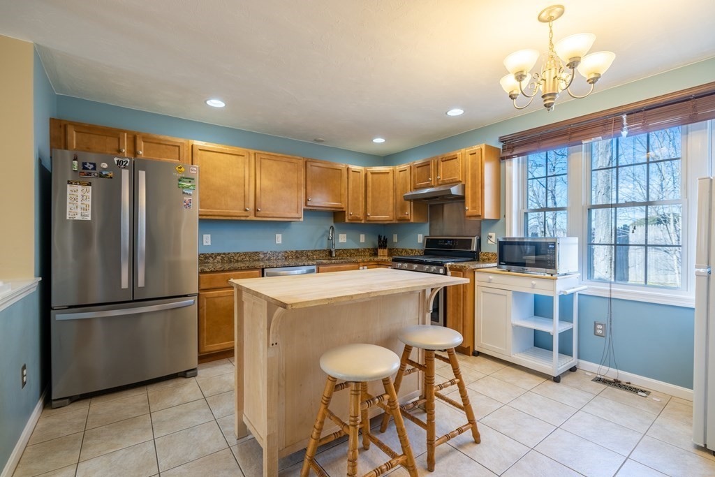 90 Central Street, Unit 2 East Bridgewater, MA 02333 - Photo 9 of 26 a kitchen with a refrigerator a microwave oven a sink and a dining table with wooden floor
