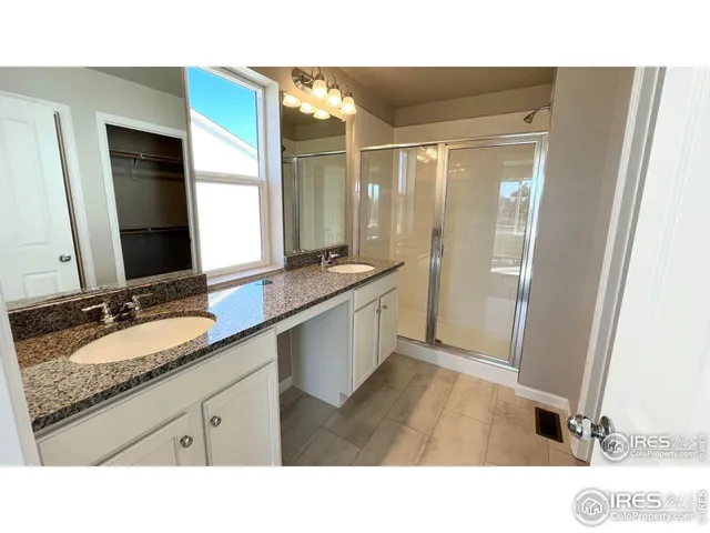 a bathroom with a sink double vanity granite and a mirror