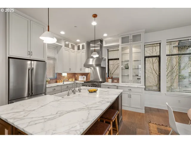 a kitchen with stainless steel appliances kitchen island granite countertop a refrigerator a sink dishwasher with a dining table and chairs