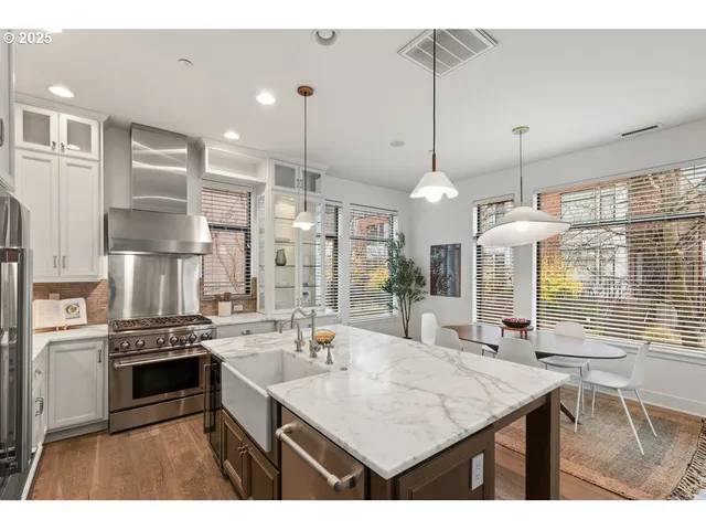 a kitchen with stainless steel appliances kitchen island granite countertop a sink a stove and a wooden floors
