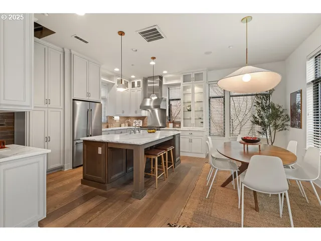 a kitchen with kitchen island a dining table chairs stainless steel appliances and cabinets