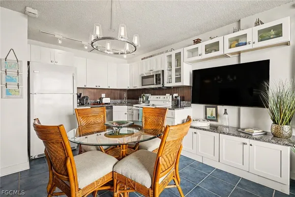 a dining room with furniture a chandelier and kitchen view