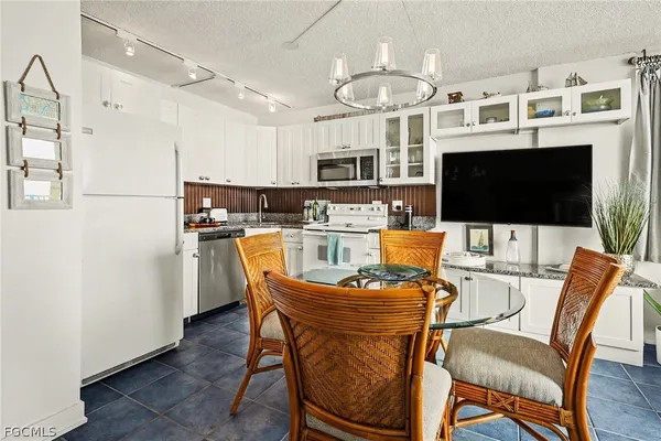 a kitchen with stainless steel appliances kitchen island granite countertop a dining table chairs microwave and sink