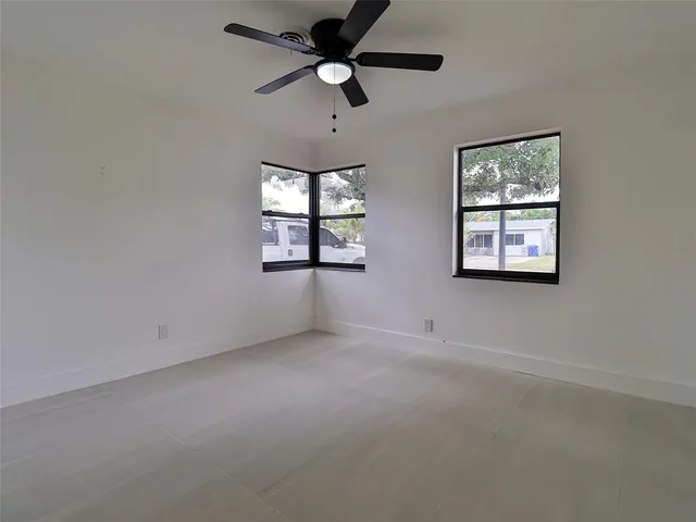 an empty room with windows and fan