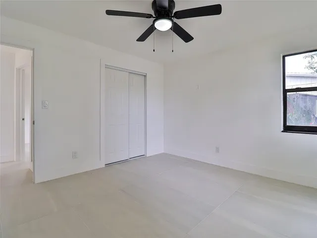an empty room with windows and fan