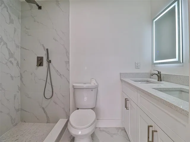 a bathroom with a granite countertop toilet sink and mirror