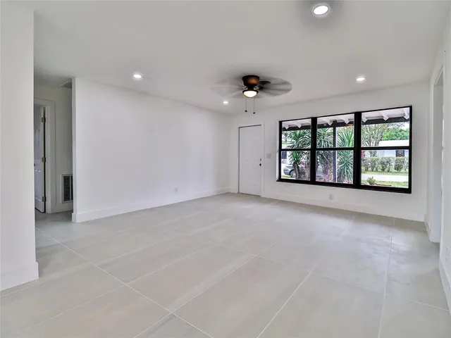 an empty room with windows and ceiling fan