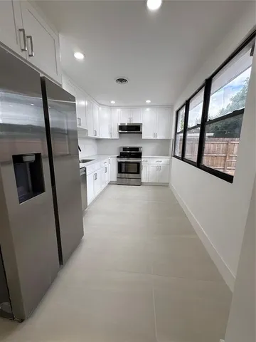 a kitchen with stainless steel appliances a refrigerator a stove a sink and a window