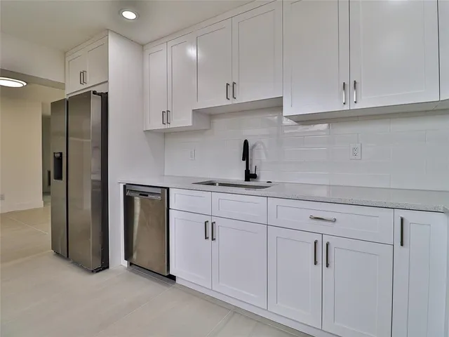 a kitchen with stainless steel appliances granite countertop white cabinets and a refrigerator