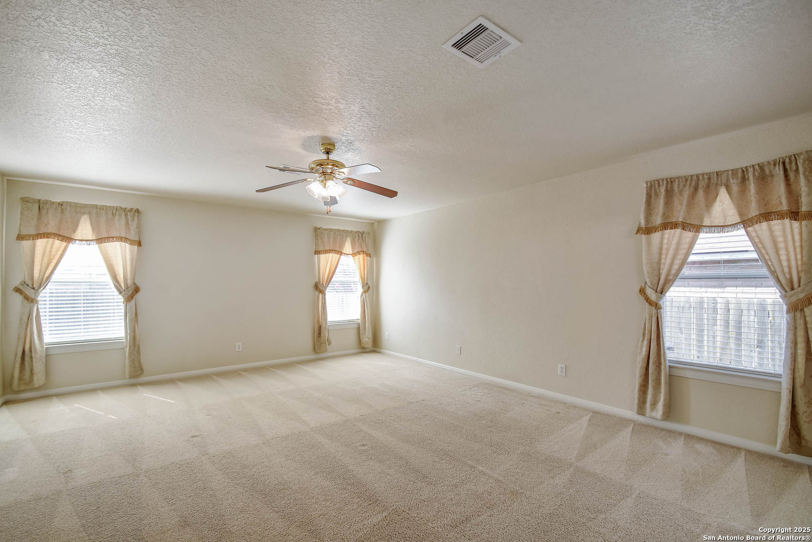 184 Springtree Parkway Cibolo, TX 78108 - Photo 19 of 36 an empty room with windows and chandelier fan