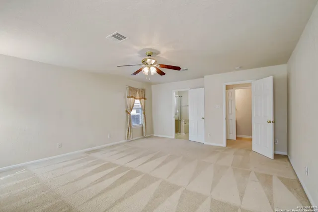 a view of a livingroom with a chandelier fan and windows
