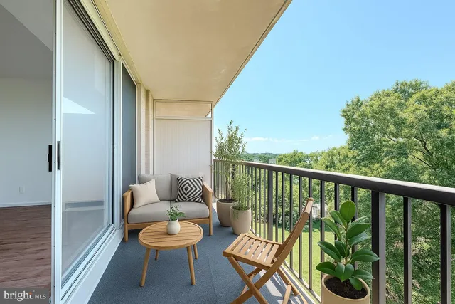 a balcony with chairs and a potted plant