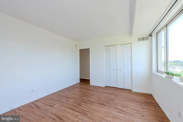 a view of an empty room with wooden floor and a window