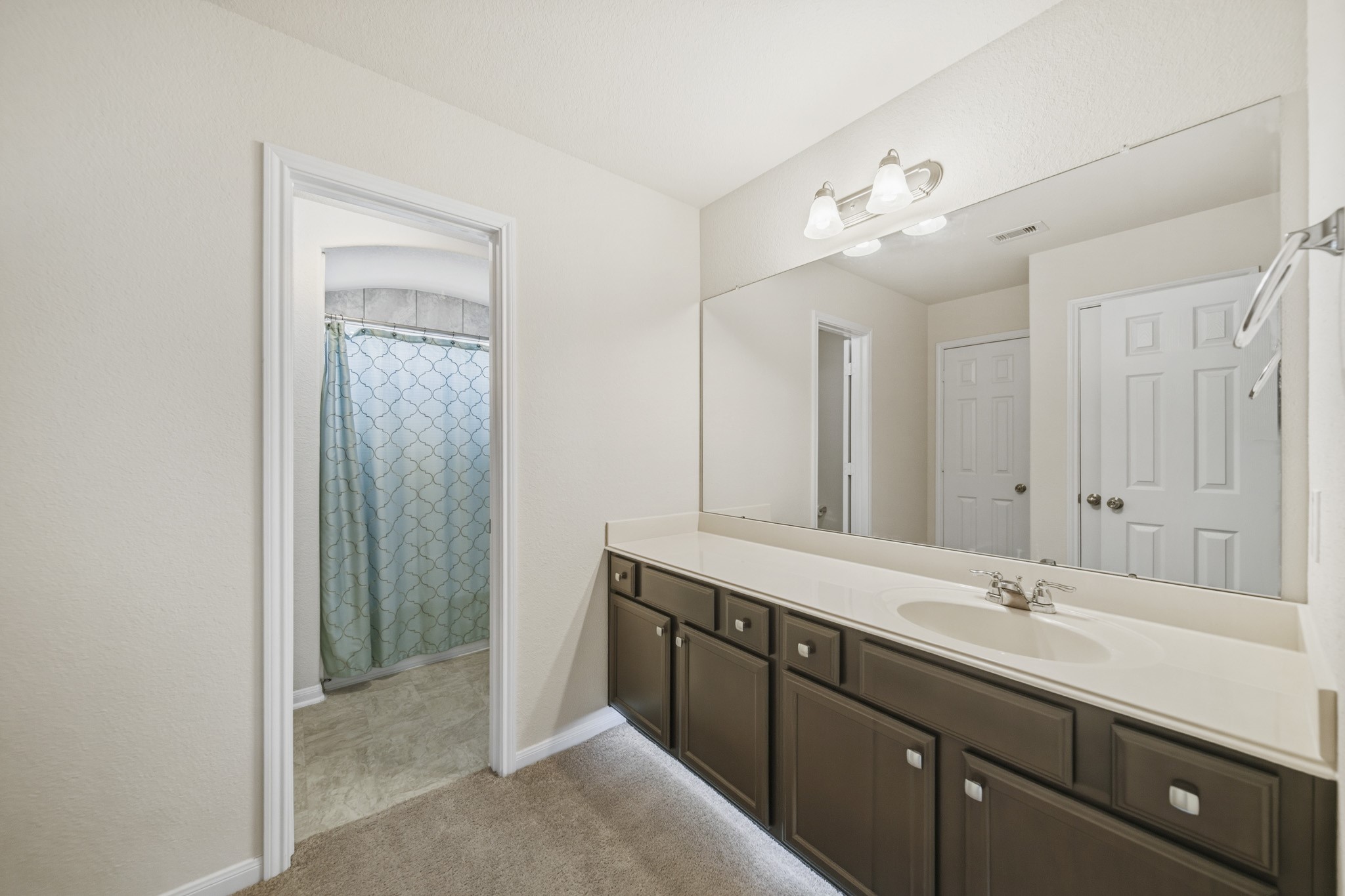 3010 Coachmaker Trail Rosenberg, TX 77471 - Photo 16 of 26 Lovely secondary bathroom complete with a large mirror, countertops and wooden cabinets, and a shower/tub combo.