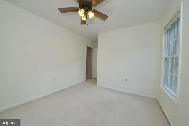an empty room with a chandelier fan and windows