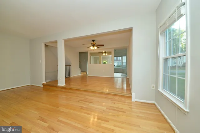 a view of an empty room with window and wooden floor