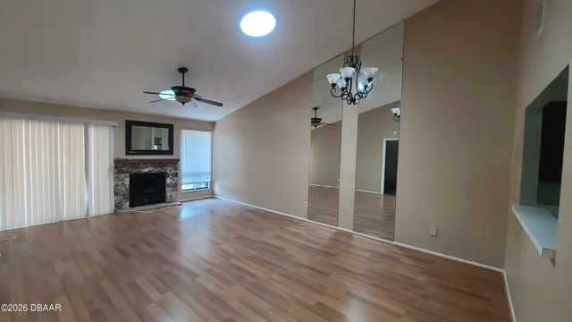 a view of a livingroom with a chandelier wooden floor and a kitchen