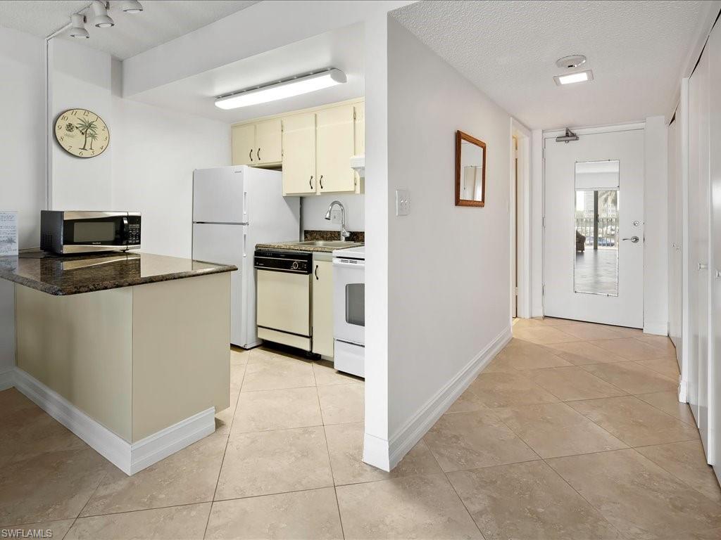 1 Bluebill Avenue, Unit 302 Naples, FL 34108 - Photo 9 of 21 a kitchen with a refrigerator and a stove top oven