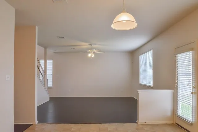 a view of an empty room with wooden floor and fan