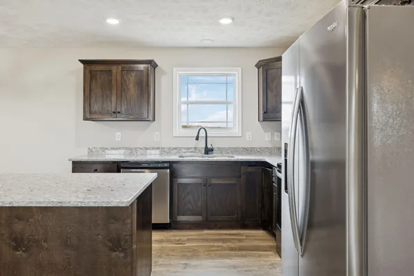 a kitchen with stainless steel appliances kitchen island granite countertop a stove top oven a sink a counter space and cabinets