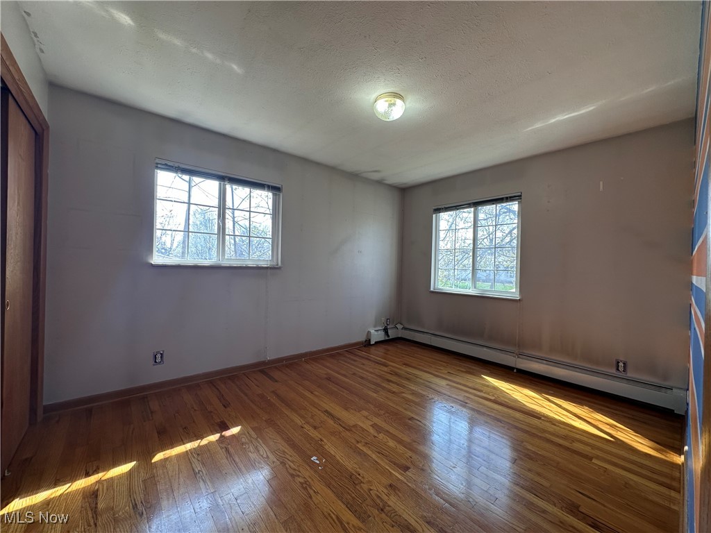 2829 Shellhart Road Barberton, OH 44203 - Photo 9 of 29 Upper level unfurnished bedroom featuring baseboards, hardwood / wood-style floors, and baseboard heating