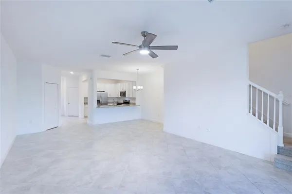 an empty room with a ceiling fan and windows
