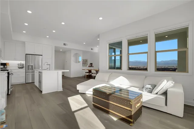 a living room with stainless steel appliances kitchen island furniture and a wooden floor