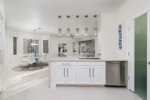 a large white kitchen with kitchen island white cabinets and stainless steel appliances