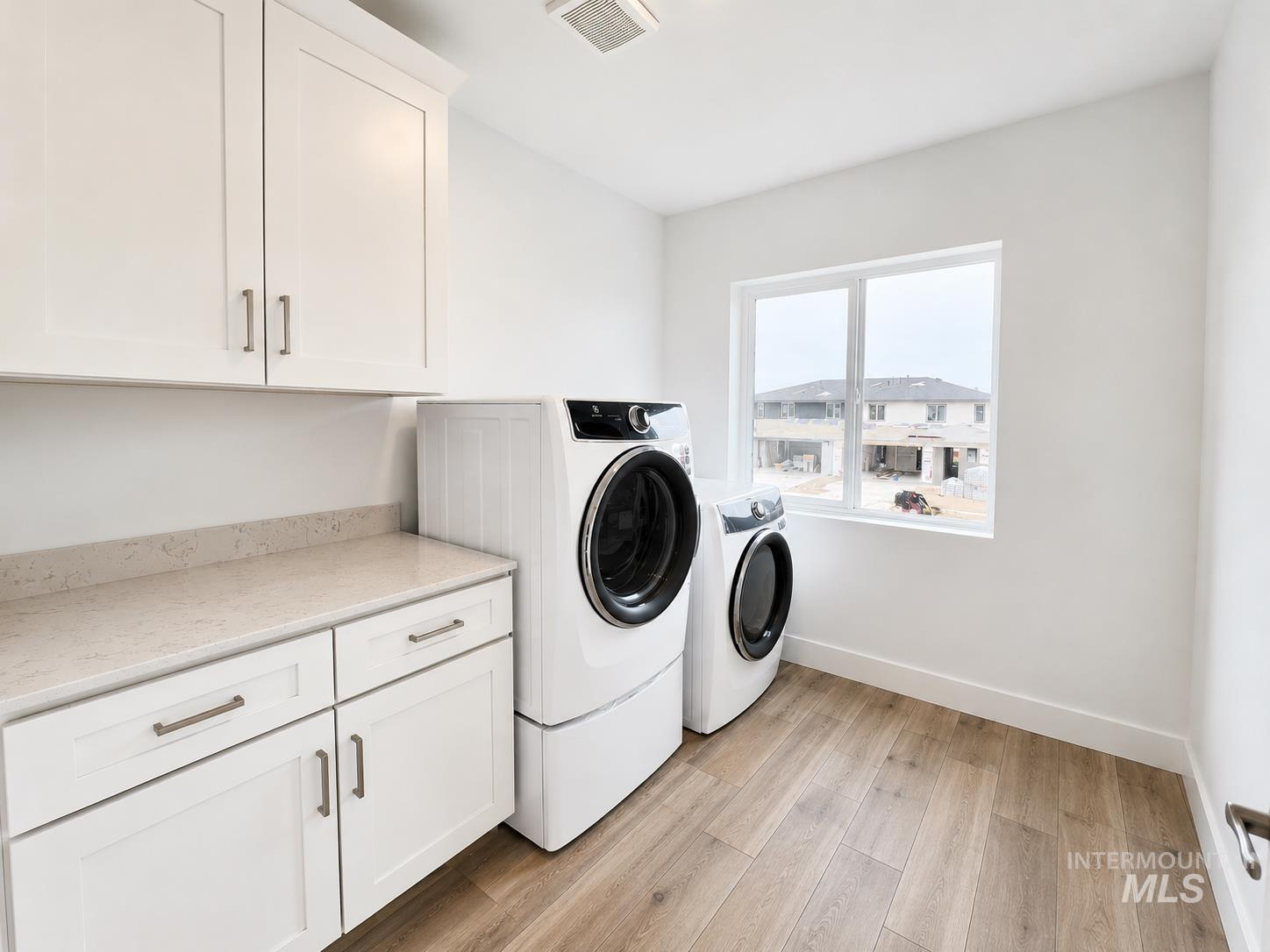 8098 West Fern Street Eagle, ID 83616 - Photo 9 of 22 Laundry room featuring white shaker cabinetry, light-toned countertop, and wood-finish flooring