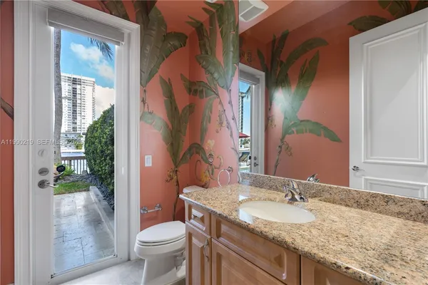 a bathroom with a granite countertop sink toilet and mirror