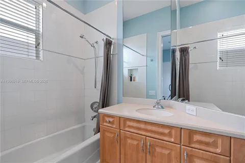 a bathroom with a granite countertop sink a mirror and a bathtub