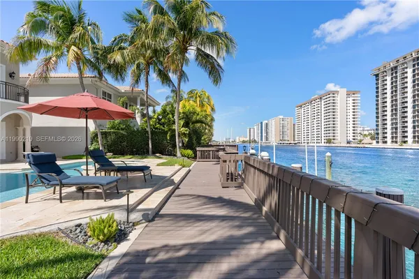 a view of a patio with a table and chairs under an umbrella with palm trees