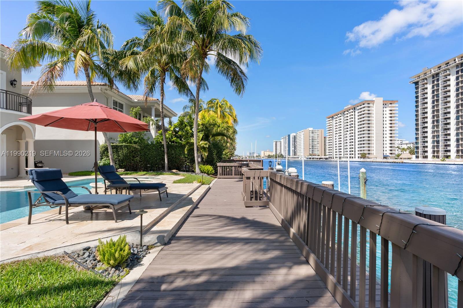1495 Windjammer Way Hollywood, FL 33019 - Photo 40 of 48 a view of a patio with a table and chairs under an umbrella with palm trees