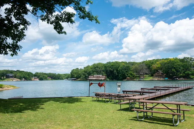 a view of a lake with a bench and trees in the background