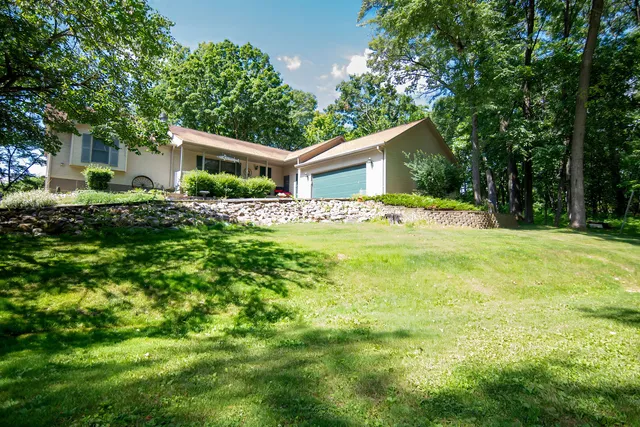 a view of a house with a big yard and large trees