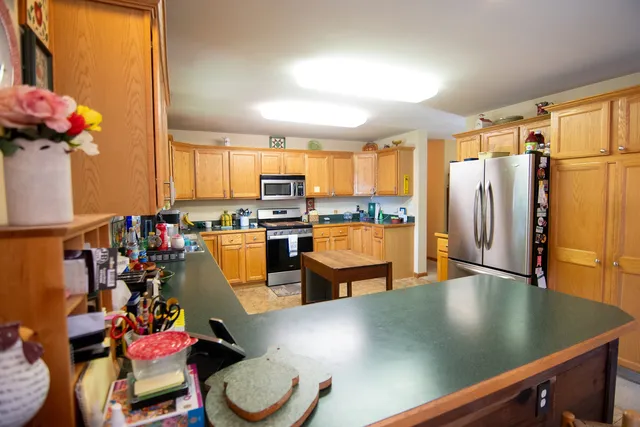 a kitchen with stainless steel appliances granite countertop a refrigerator a sink dishwasher a dining table and chairs with wooden floor