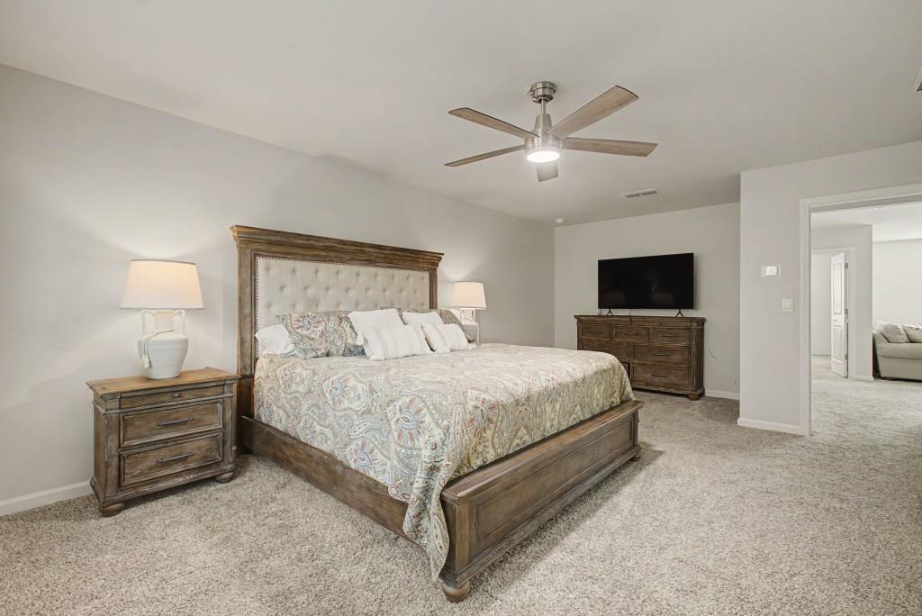 87 Cranson Walk Pendergrass, GA 30567 - Photo 29 of 50 a spacious bedroom with a bed and a chandelier