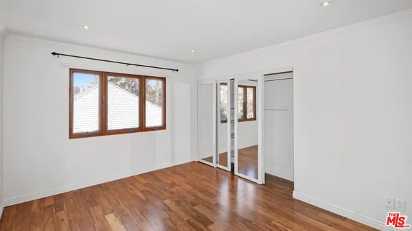 a bedroom with a bed wooden floor and window