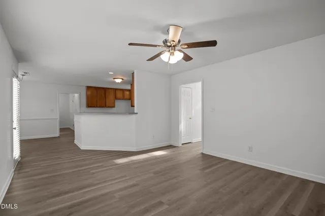 a view of empty room with wooden floor and fan