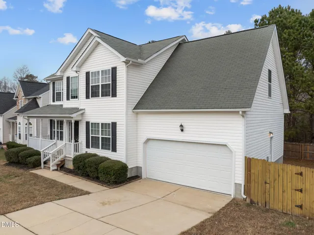 a view of a white house with a yard and potted plants