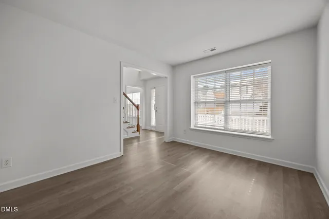 a view of an empty room with wooden floor and windows