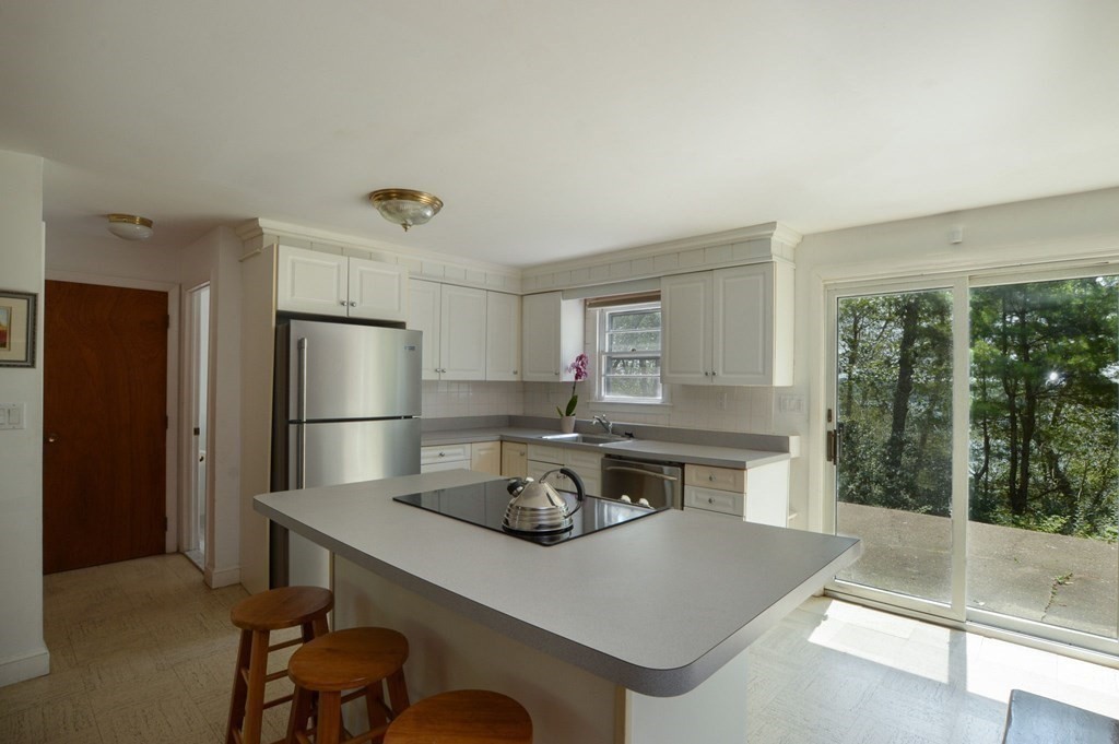230 Pimlico Pond Road Mashpee, MA 02649 - Photo 14 of 35 a kitchen with a table chairs refrigerator and trees