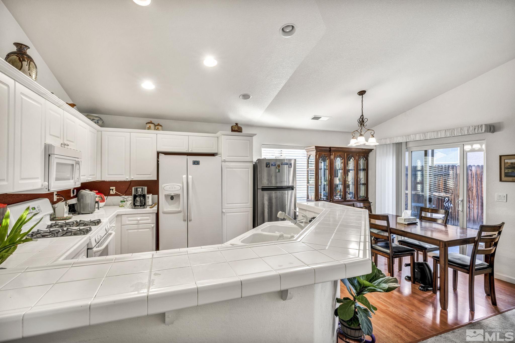 1770 Ornellaia Way Reno, NV 89521 - Photo 28 of 37 a kitchen with stainless steel appliances kitchen island granite countertop a refrigerator and a dining table