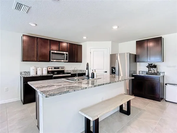 a kitchen with stainless steel appliances granite countertop a refrigerator a stove a sink a microwave and a refrigerator