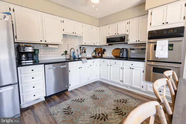 a kitchen with granite countertop a sink a stove a oven and white cabinets